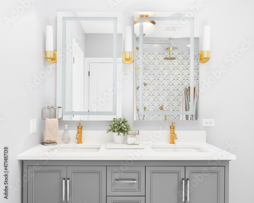 Tableau sur toile A bright, modern bathroom with a grey vanity cabinet, gold faucets and light fixtures, granite countertop, and a view to a gorgeous tiled walk-in shower