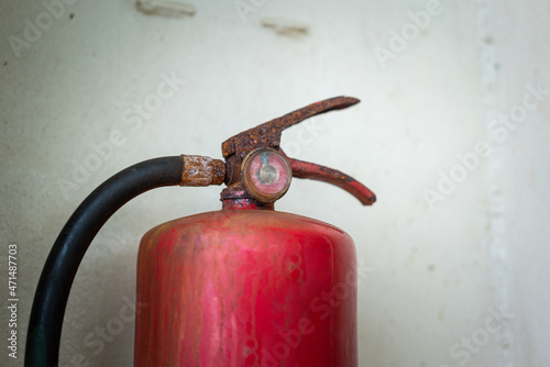 A very old chemical fire extinguisher which rusty handle and dirty pressure gauge. Emergency equipment object photo. Selective focus at pressure gauge.