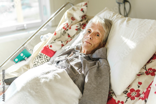 Sick, elderly senior woman in a hospital bed photo