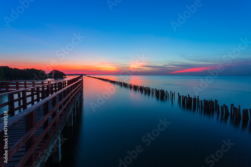 Crescent moon and wonderful light at golden hour before sunrise with colorful reflection at red bridge near by Tha Chin estuary, Gulf of Thailand, Samut Sakhon province, Thailand