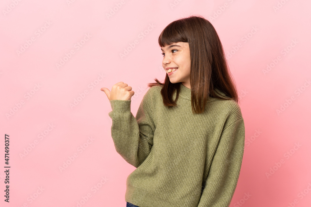Little girl isolated on pink background pointing to the side to present a product Little girl isolated on pink background pointing to the side to present a product
