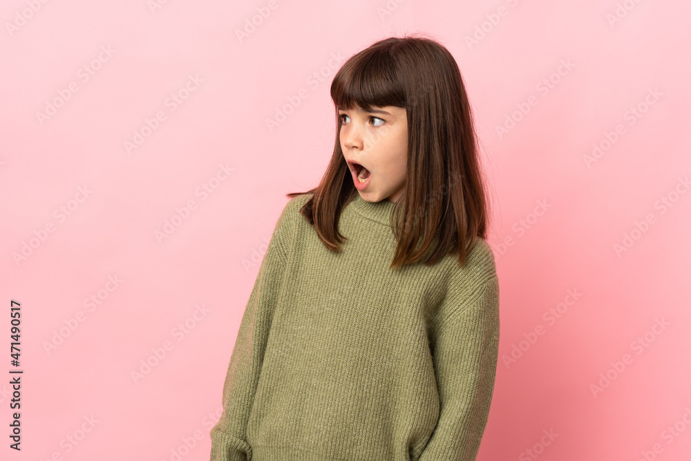 Little girl isolated on pink background doing surprise gesture while looking to the side Little girl isolated on pink background doing surprise gesture while looking to the side