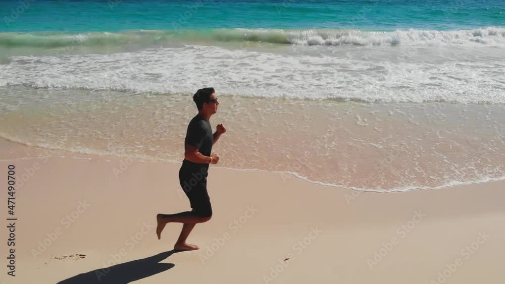 Man Runner. Fit and happy middle aged man running on the beach. Man Run. Side view shot of pretty young man barefoot in sportswear jogging on beach. Male runner jogging on outdoors on beach. Lifestyle Man Runner. Fit and happy middle aged man running on the beach. Man Run. Side view shot of pretty young man barefoot in sportswear jogging on beach. Male runner jogging on outdoors on beach. Lifestyle