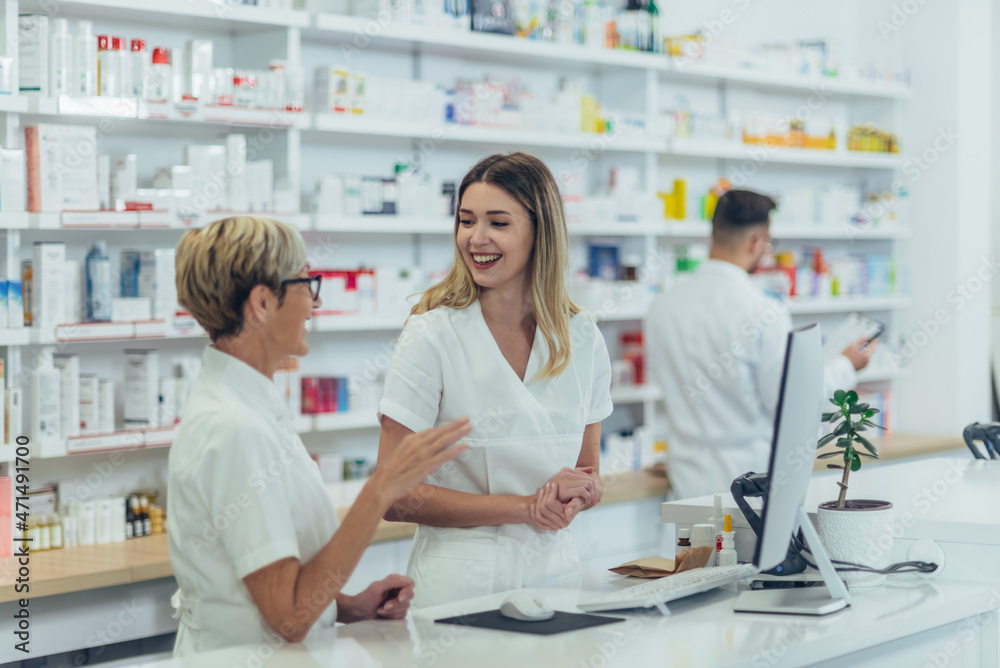 Happy young female pharmacist working with senior colleague Happy young female pharmacist working with senior colleague
