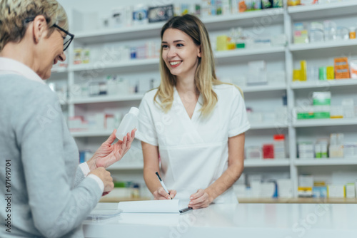 Pharmacist giving prescription medications to smiling senior female customer