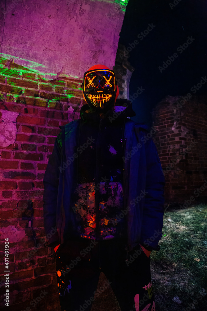 Man in creepy glowing mask in abandoned building. Horror concept