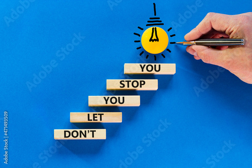 Do not let stop you symbol. Wooden blocks with words Do not let you stop you on blue background, copy space. Light bulb icon. Businessman hand with pen. Business, do not let stop you concept.