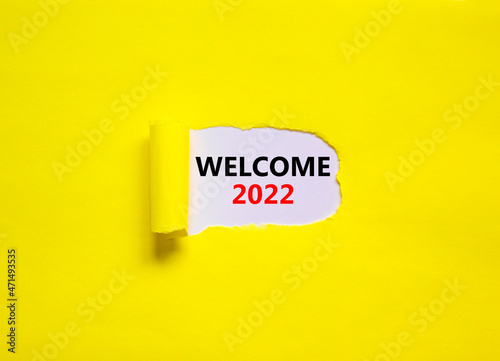 2022 welcome new year symbol. Concept words Welcome 2022 appearing behind torn yellow paper. Beautiful yellow background. Business, welcome 2022 new year concept, copy space.