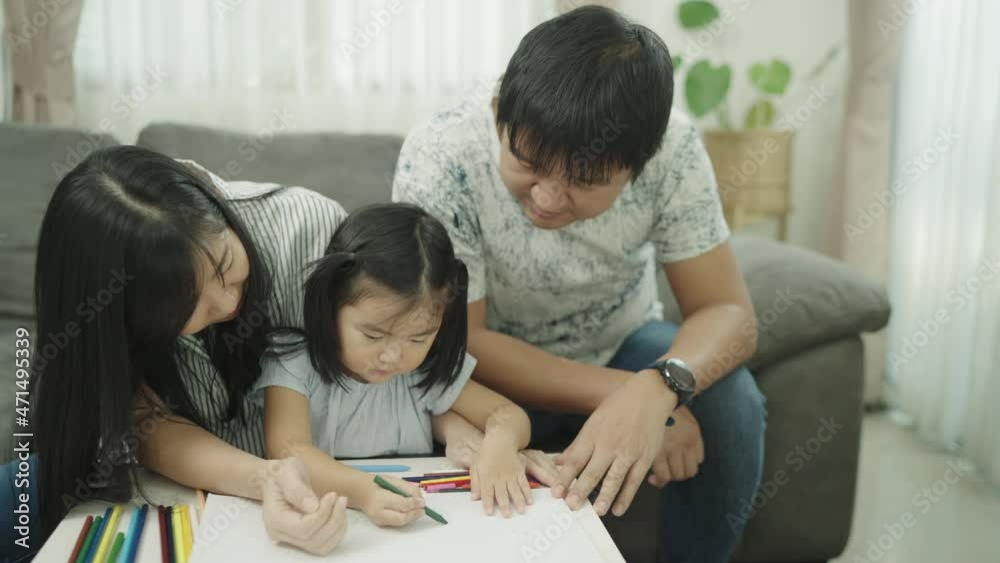Asian Family parents play with daughters at the home table. adult parent father teaching cute small children girls learning creative activity enjoying happy high five with daddy and mom on holiday. Asian Family parents play with daughters at the home table. adult parent father teaching cute small children girls learning creative activity enjoying happy high five with daddy and mom on holiday.