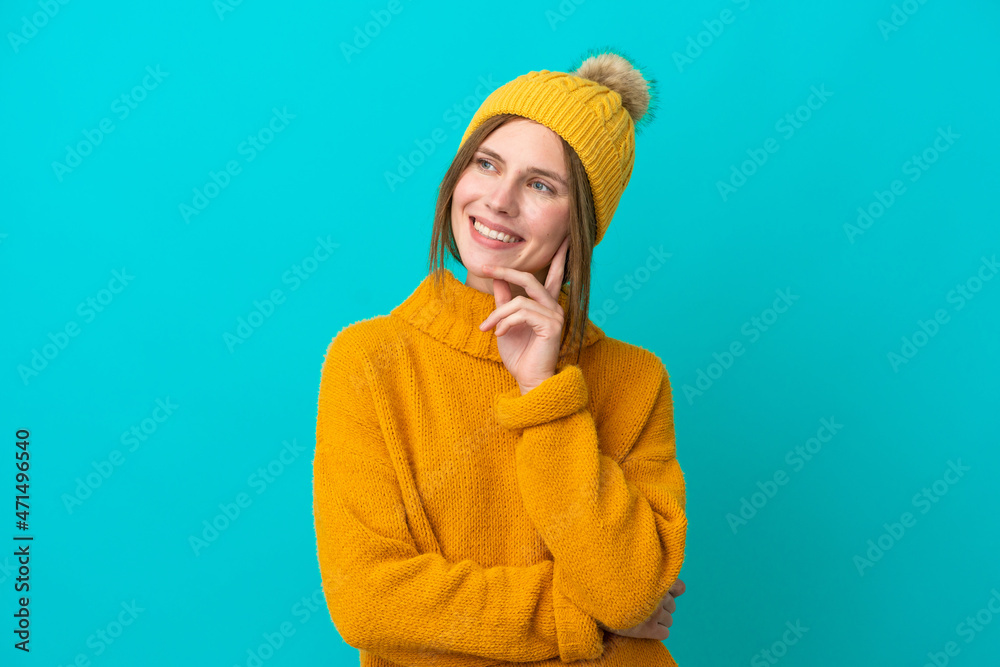 Young English woman wearing winter jacket isolated on blue background thinking an idea while looking up Young English woman wearing winter jacket isolated on blue background thinking an idea while looking up