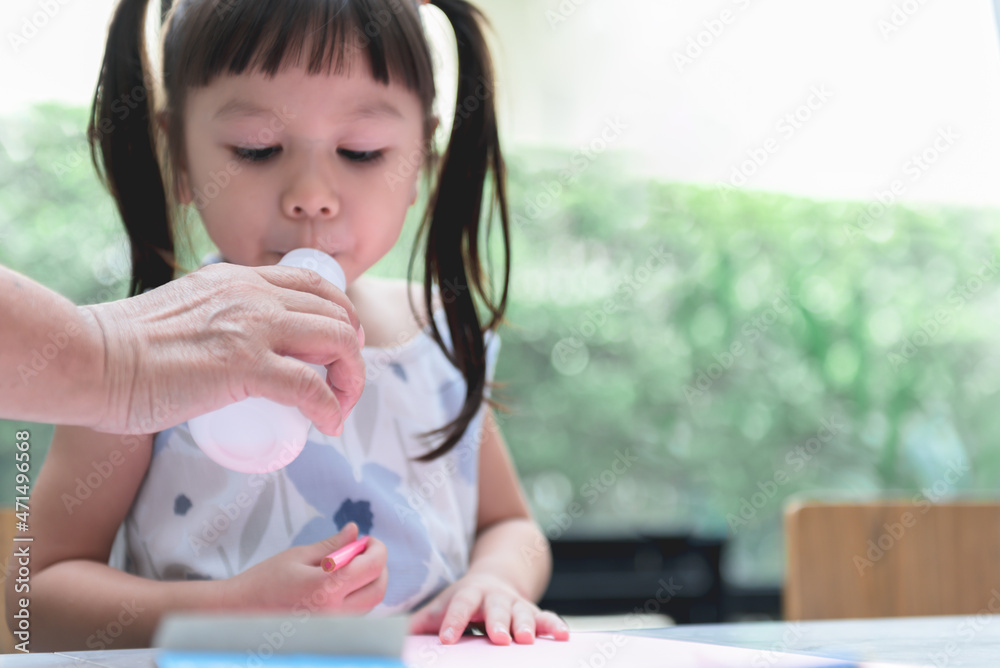 Blurred soft images of Asian girl, 3-year-old is drinking milk from a bottle, which her mother holding, to children and drink milk concept. Blurred soft images of Asian girl, 3-year-old is drinking milk from a bottle, which her mother holding, to children and drink milk concept.