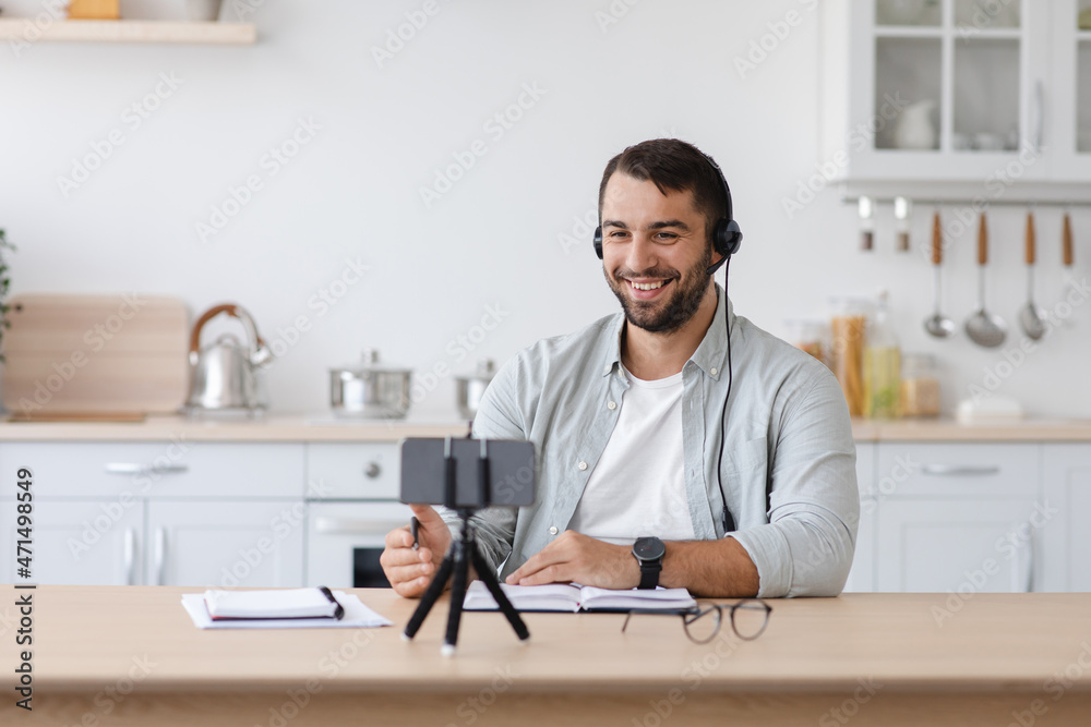 Smiling adult european male blogger with beard streaming video, look at smartphone webcam Smiling adult european male blogger with beard streaming video, look at smartphone webcam