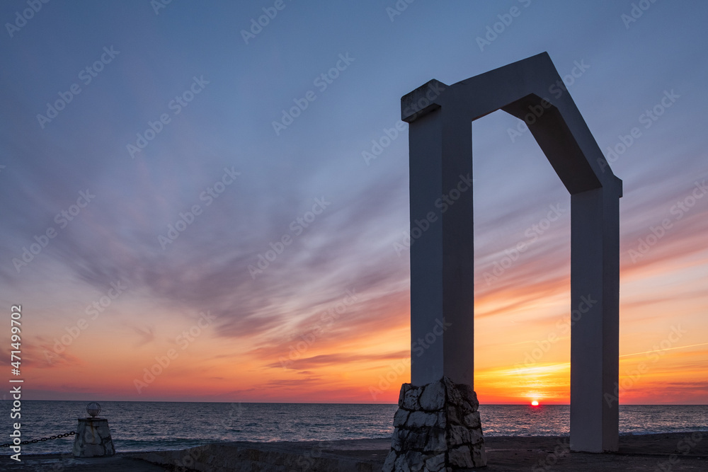 the seashore during sunset, the horizon line and the triangular arch in the foreground