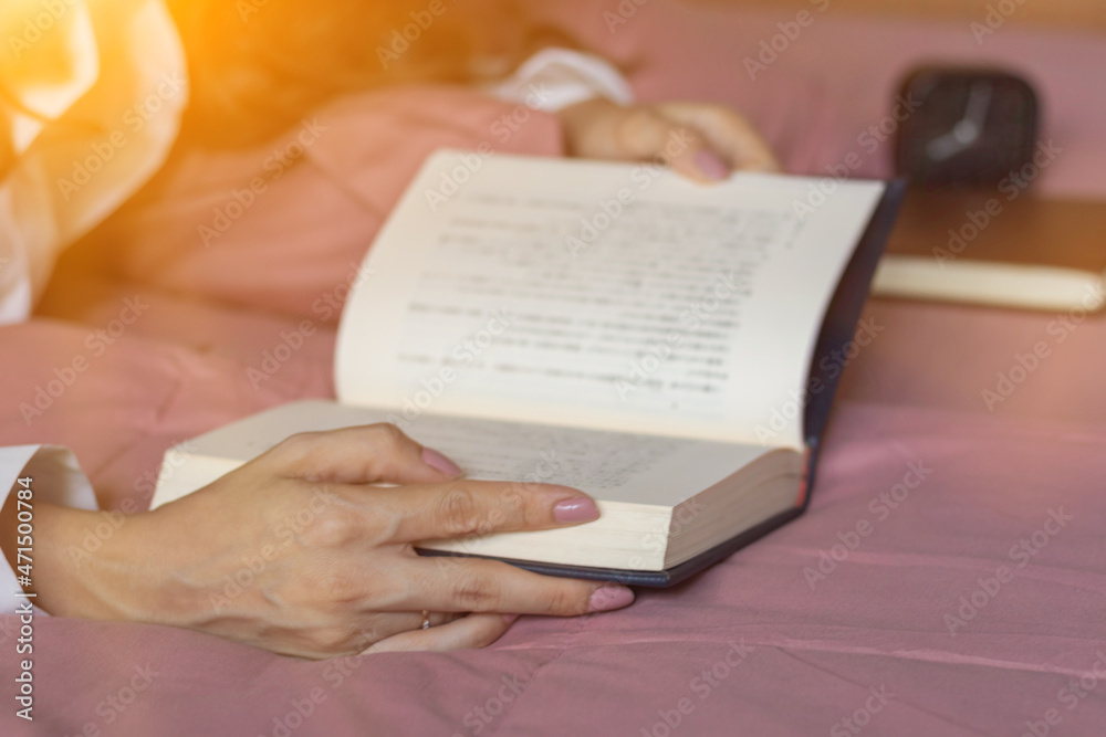 Fototapeta premium A girl is reading bible in bed to study and learn God's teachings before she goes to bed and understand for proper prayer and blessing from God with belief and power of faith in God.
