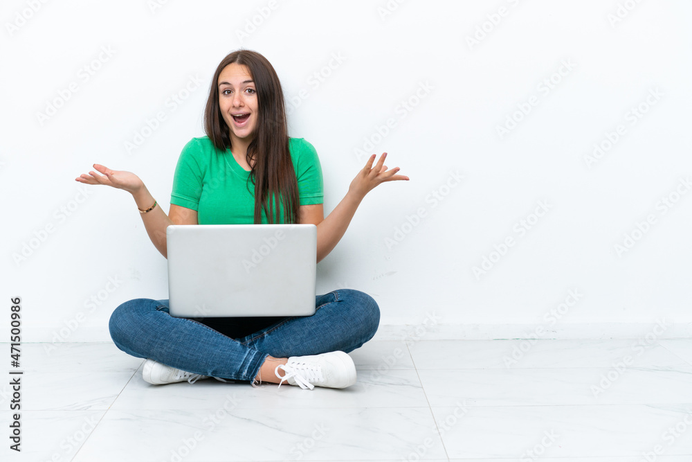 Young Ukrainian woman with a laptop sitting on floor with shocked facial expression Young Ukrainian woman with a laptop sitting on floor with shocked facial expression