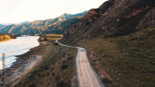 White car drives through narrow road in the mountains. Drone footage photo