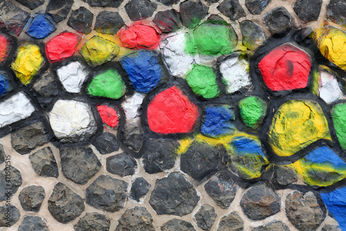 Stone wall with pattern.Individual stones of a stone wall are painted with bright colours
