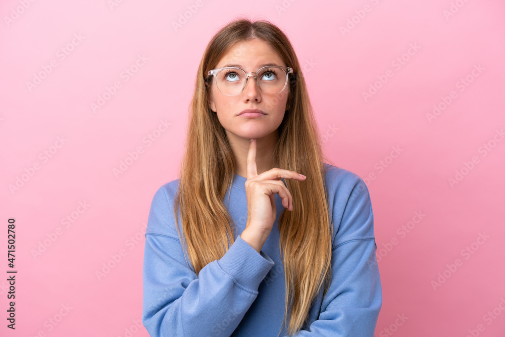 Young blonde woman isolated on pink background With glasses and looking up Young blonde woman isolated on pink background With glasses and looking up