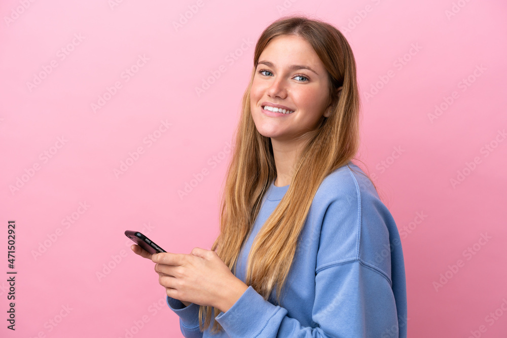 Young blonde woman isolated on pink background sending a message or email with the mobile Young blonde woman isolated on pink background sending a message or email with the mobile