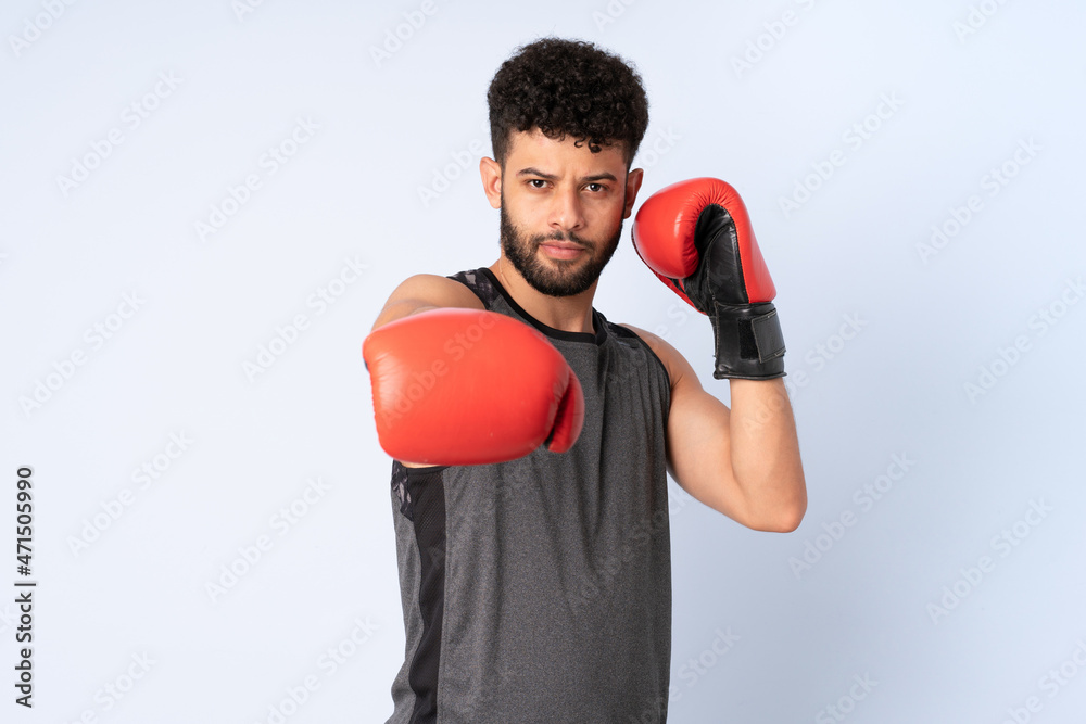 Young Moroccan man isolated on blue background with boxing gloves