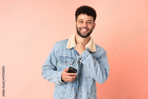 Young Moroccan man using mobile phone isolated on pink background celebrating a victory © luismolinero