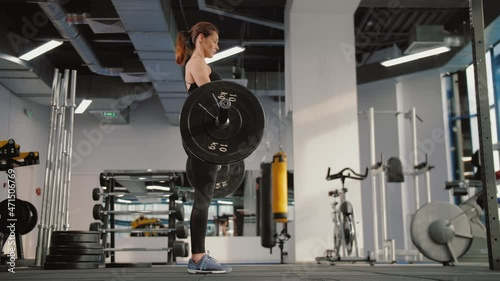 Fit young woman doing deadlift with heavy bar in gym, strong female athlete with muscular sexy body lifting weights, exercising with barbell. Concept of sport, beauty, health, lifestyle.  photo