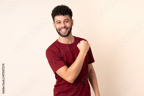 Young Moroccan man isolated on beige background celebrating a victory