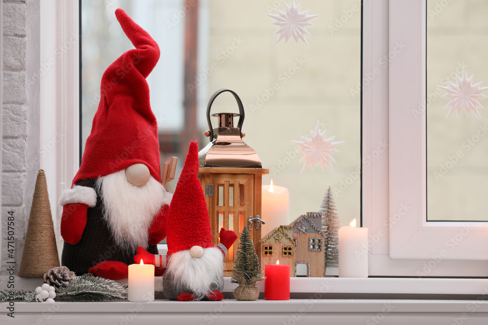 Obraz premium Cute Christmas gnomes and other festive decorations on windowsill in room, space for text