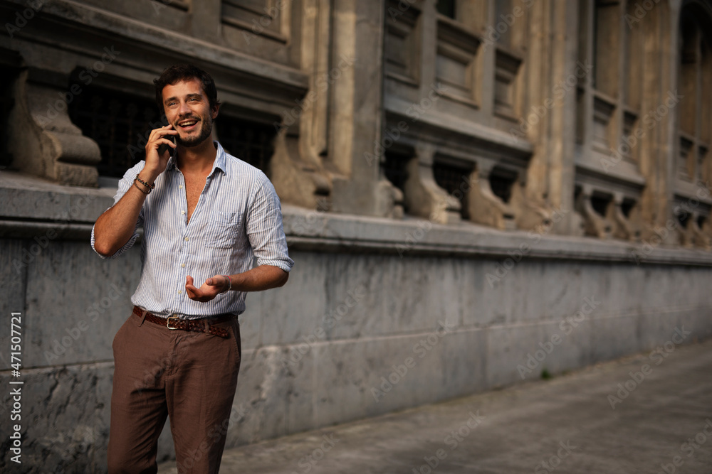 Young modern man using the phone outdoors. Fashion happy man enjoy outdoors..