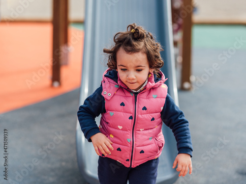 Little girl having fun while enjoying playing in a playground in a park. Childhood concept.