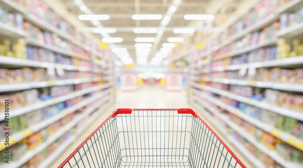 Empty red shopping cart with supermarket grocery store interior aisle abstract blurred background