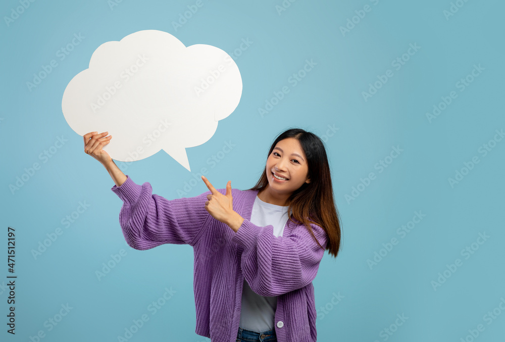 Happy asian lady pointing at empty speech bubble, smiling at camera on blue studio background, mockup Happy asian lady pointing at empty speech bubble, smiling at camera on blue studio background, mockup