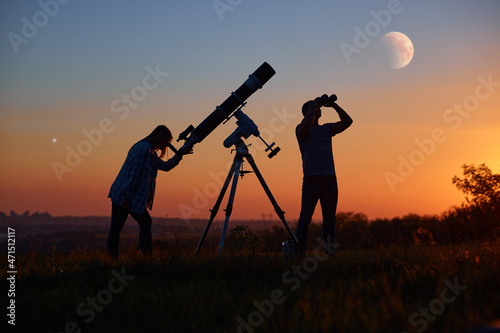 Bilde på lerret Couple stargazing together with a astronomical telescope, looking at planets, stars, lunar eclipse and meteor shower