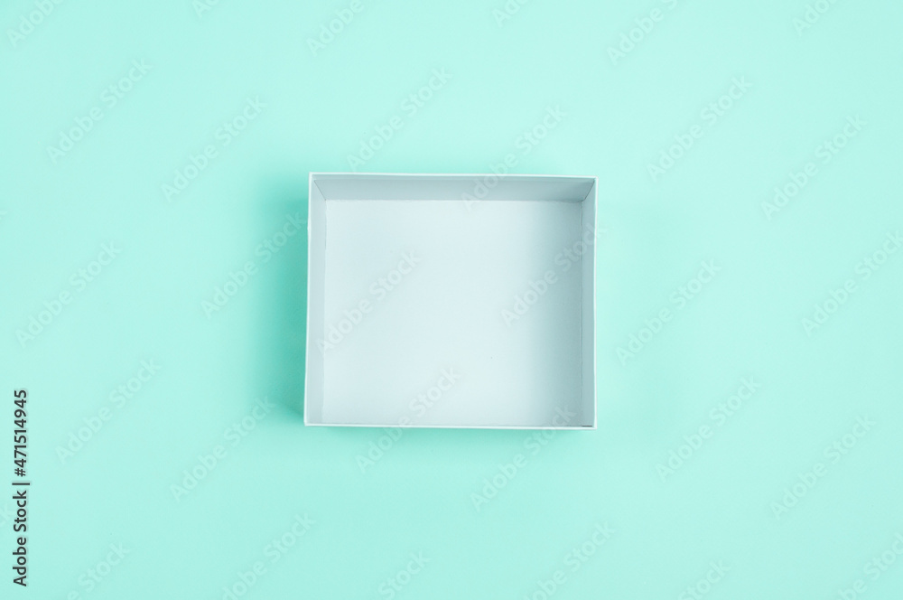 Open box with stuff in blue background. Yellow paper stuff in empty box. Minimalist composition. Copy space. Open box with stuff in blue background. Yellow paper stuff in empty box. Minimalist composition. Copy space.
