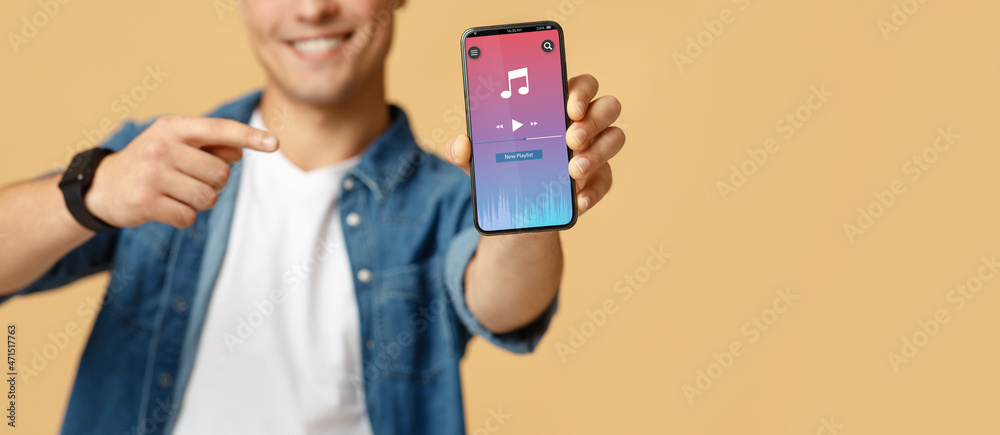 Music Player Ad. Unrecognizable Young Guy Showing Smartphone With Mobile Application Interface Music Player Ad. Unrecognizable Young Guy Showing Smartphone With Mobile Application Interface