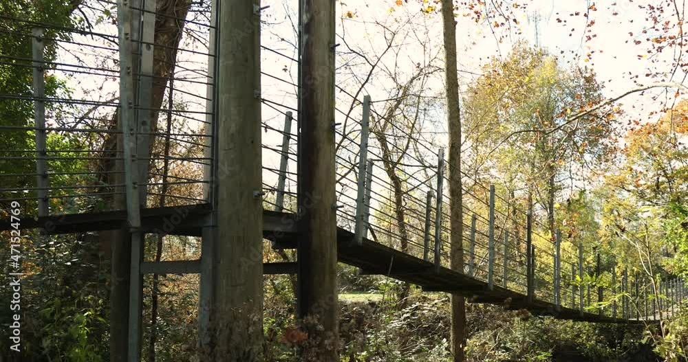 Large Suspension bridge over a river in the woods during the autumn season. Shot in 4k slow motion. Large Suspension bridge over a river in the woods during the autumn season. Shot in 4k slow motion.