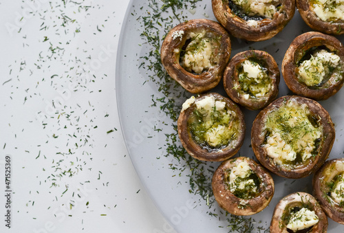 A dish full of mushrooms stuffed with butter, cheese and spices on a wooden kitchen table