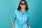 Young woman in a blue shirt on a background in sunglasses, fashionably stylish posing