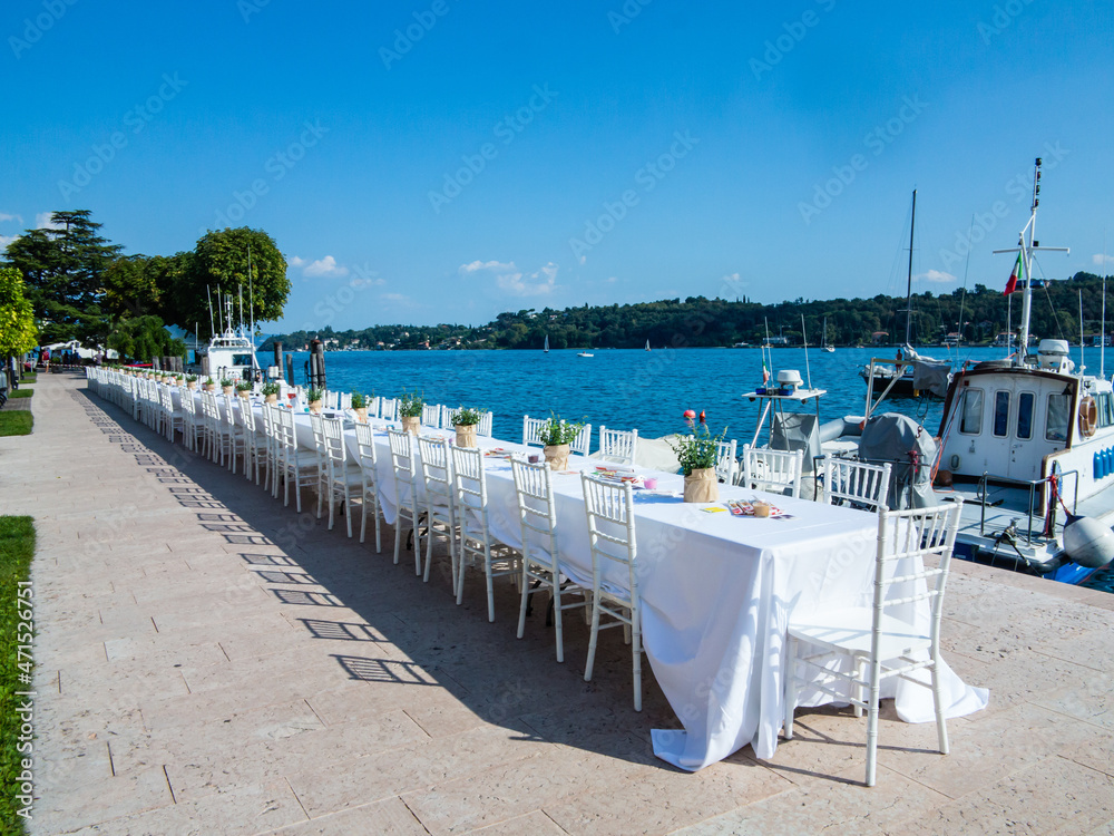 Long table for a dinner event at the edge of the Lake in Salò-Garda lake-Italy