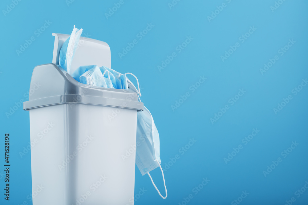Waste bin full of used protective masks on a light blue background with  free space. Stock Photo | Adobe Stock