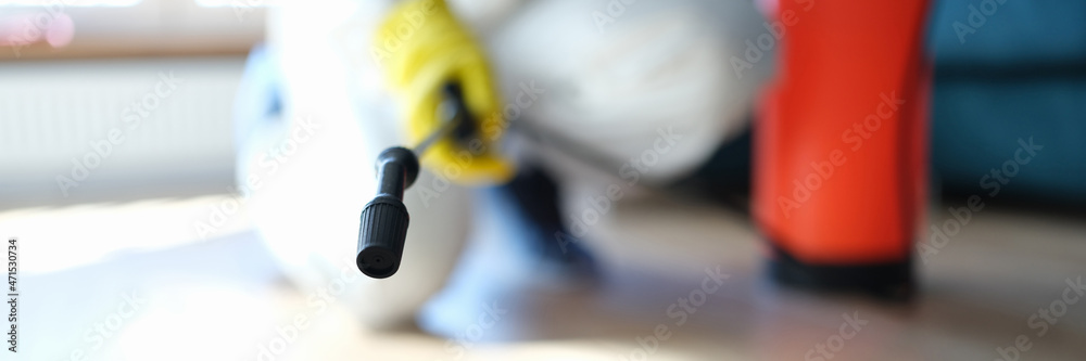 Man in protective suit treating floor in apartment with disinfectant closeup Man in protective suit treating floor in apartment with disinfectant closeup
