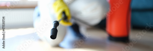 Fotografie Man in protective suit treating floor in apartment with disinfectant closeup