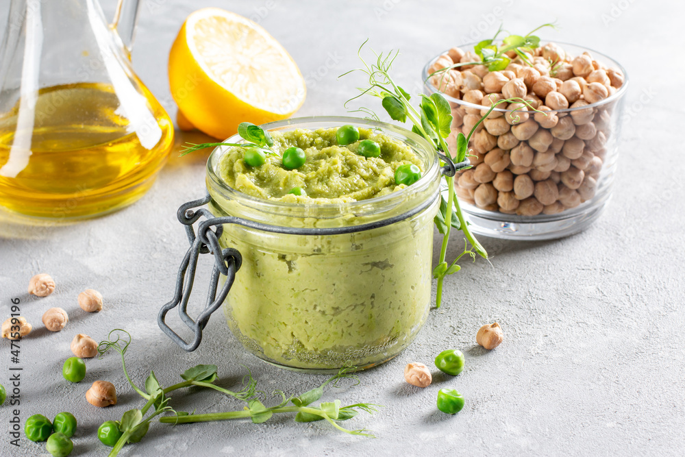 Glass jar of green hummus, delicious cream of chickpeas and green pea. Vegetarian snack. Copy space Glass jar of green hummus, delicious cream of chickpeas and green pea. Vegetarian snack. Copy space