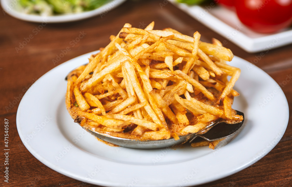 French fries with sauce in a metal bowl.Golden potatoes prepared with deep-frying