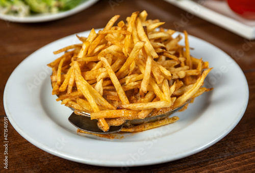 French fries with sauce in a metal bowl.Golden potatoes prepared with deep-frying