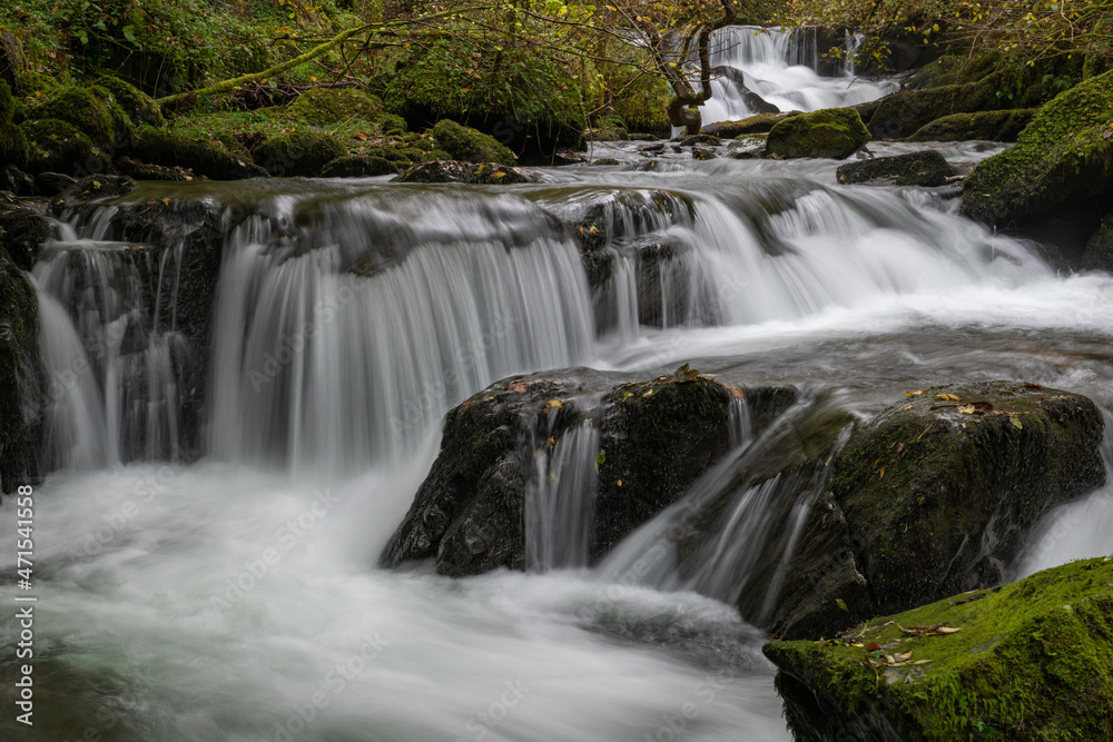 Long exposure of a waterfall flowing through the woods at Watersmeet in Exmoor National Park