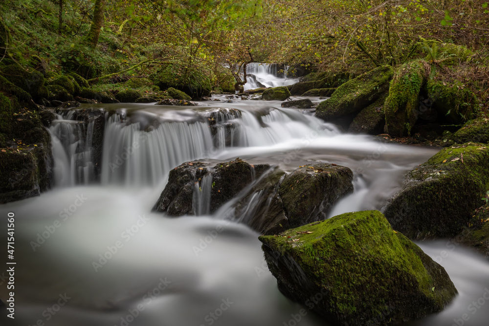 Fototapeta premium Long exposure of a waterfall flowing through the woods at Watersmeet in Exmoor National Park