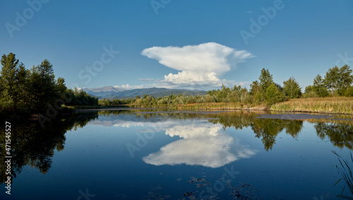 A strange cloud is reflected in the water of a lake. The lake is located in Gorj, Romania.
