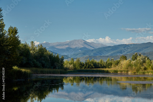 Mount Parang is reflected in the water of a lake near Bumbesti-Jiu, Romania.