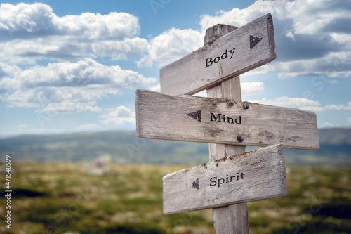 body mind spirit text quote on wooden signpost outdoors in nature. Blue sky above. © Jon Anders Wiken